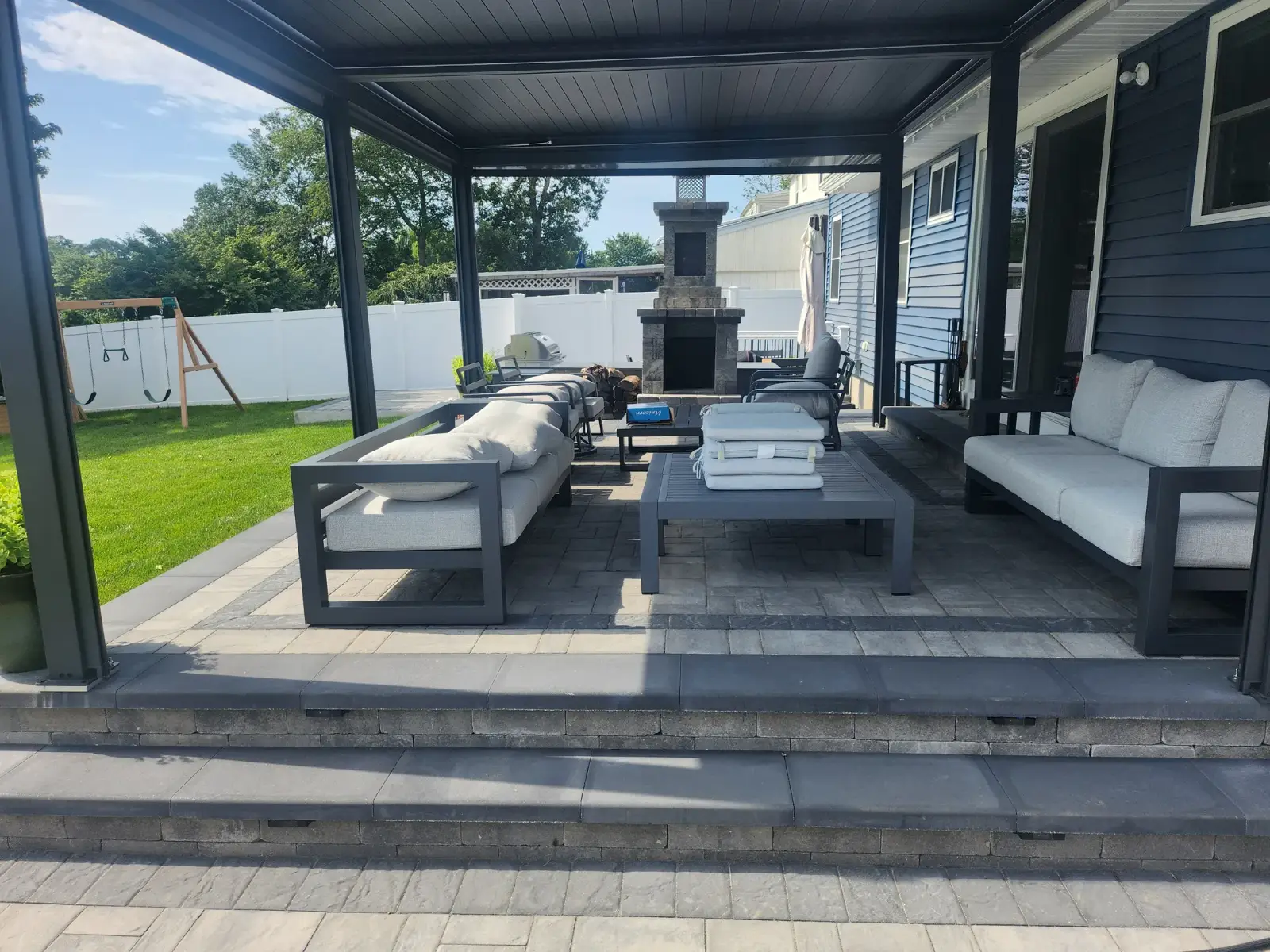 Covered paver patio with outdoor fireplace by Promaster Maintenance Corp, Long Island, NY